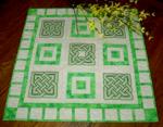 Quilted tabletopper with Celtic knots embroidery.