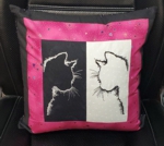 Black and pink pillow with black and white embroidered center. Embroidery design is cat silhouettes.