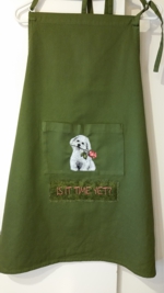 A green apron with the embroidery of a puppy on its pocket.