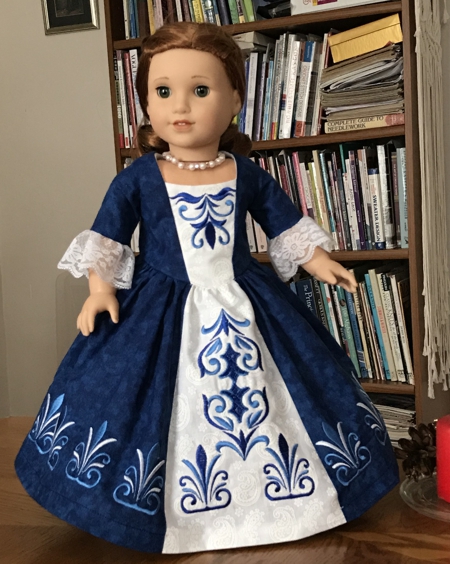Photo of a 18-inch doll modelling the formal colonial dress decorated with the machine embroidery
