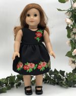 A doll in a black dress with flower embroidery.