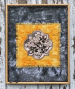 A frame with acorn embroidery on gold and gray background