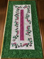 A quilted tablerunner with bleeding heart flowers embroidery in pink and green colors