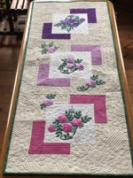 Finished quilted tablerunner with embroidery of camellias in pink, lilac and purple shades