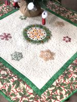 Christmas-themed quilted tabletopper with snowflake embroidery.