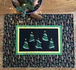 Christmas-themed wall quilt with embroidery of fir trees on the black background.