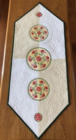 Light-colored tablerunner with triangular ends and rose embroidery