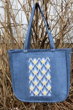 Blue denim tote bag with embroidered front and back panels.