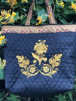 A black tote bag made of pre-quilted fabric and embellished with flower embroidery