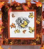 Small wall quilt in autumn colors with golden retriever embroidery in the center.