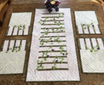 Light-colored tablerunner and placemats with grape vine embroidery