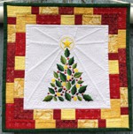 A small Christmas-themed quilt made of white, golden, red and green scraps with embroidery of a Chritmas tree in the center.
