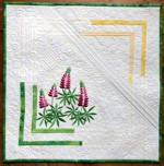 A small pale yellow quilt with bright-colored lupine flowers embroidery