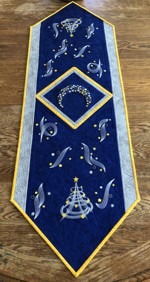 Royal blue quilted tablerunner with embroidery of a moon, stars and Christmas trees in silver and golden colors
