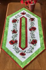 White-and-green tablerunner with poppy embroidery.
