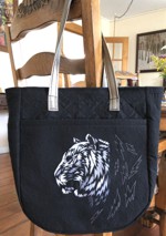 A quilted black tote bag with silver tiger embroidery