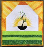 Small wall quilt with a tree embroidery and rising sun in the background