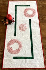 White tablerunner with red poinsettia embroidery.