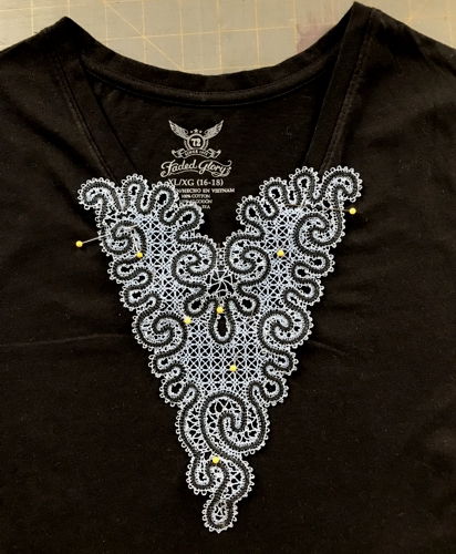 Photo of the T-shirt with V-neck and a stitch-out of the design pinned over the V-neck.