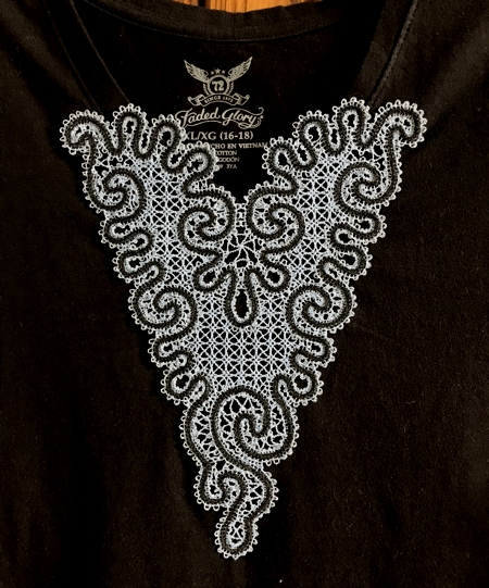 Photo of the T-shirt with V-neck and a stitch-out of the design stitched over the V-neck. Close-up.