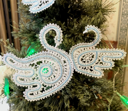 Photo of the stitch-outs of both swan designs on a Christmas tree branch