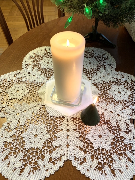 Photo with the finished doily decorating a Christmas table with candles in the center