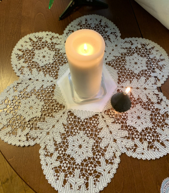Photo with the finished doily decorating a Christmas table with candles in the center