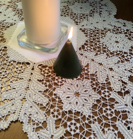 Photo, close-up, of the finished doily decorating a Christmas table with candles in the center