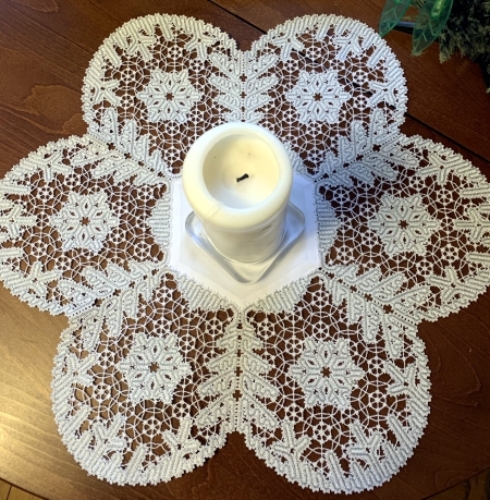 Photo with the finished doily decorating a Christmas table with a candle in the center
