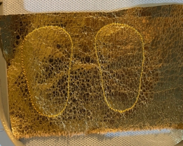 Outlines of shoe soles on a piece of fabric.