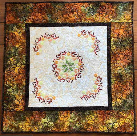 Finished quilted tabletopper featuring leaf embroidery in the central part.