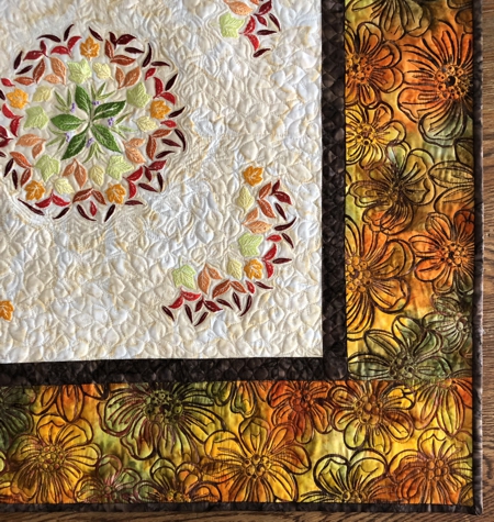 Finished quilted tabletopper featuring leaf embroidery in the central part. Close-upof the border.