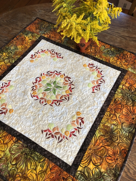 Finished quilted tabletopper featuring leaf embroidery in the central part.