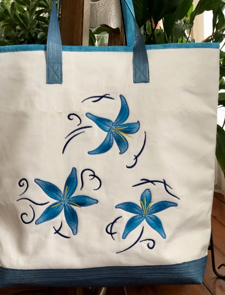 Finished white canvas bag with blue lilies embroidery. Close-up of the embroidery.