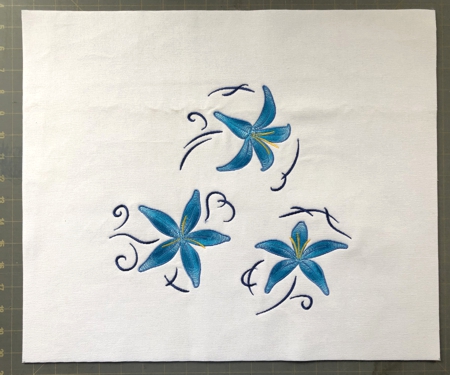 Blue lilies embroidery on white canvas. Front panel of the bag.