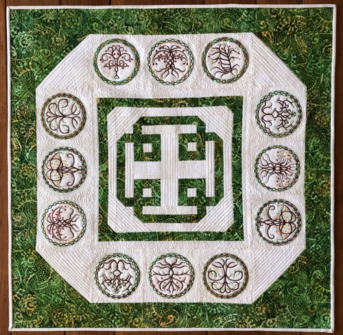 Finished tabletopper with celtic knot in the center and embroidery of celtic tree of life on the border.