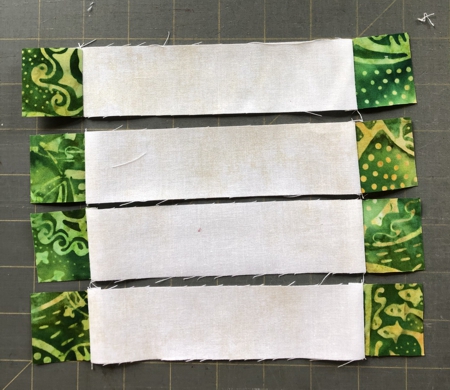 Sew the green 1 1/2" squares to the ends of the light 1 1/2" x 6 1/2" strips.