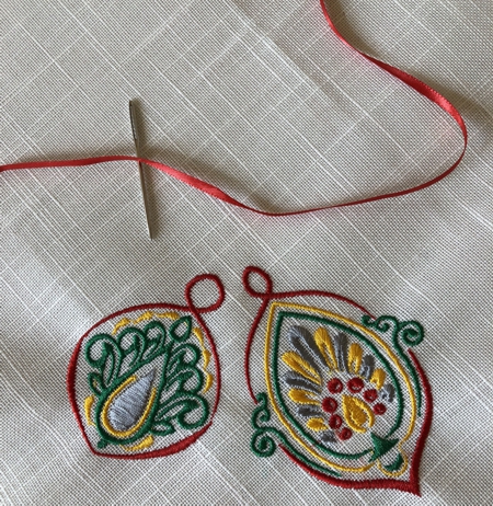 Thread tapestry needle with red ribbon.