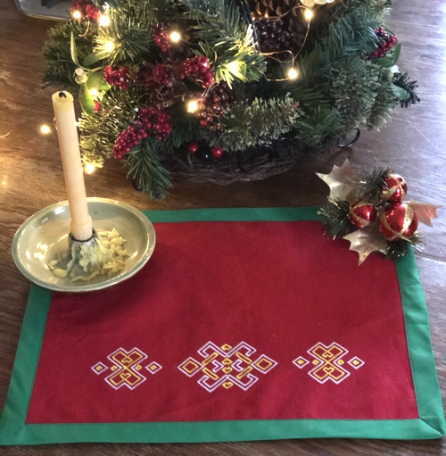 Finished placemat - red fabric, green binding and multi-colored embroidery