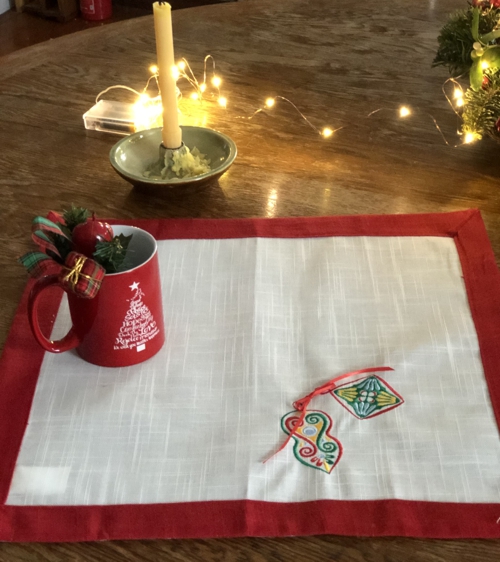 Finished placemat - white fabric, red binding and multi-colored embroidery