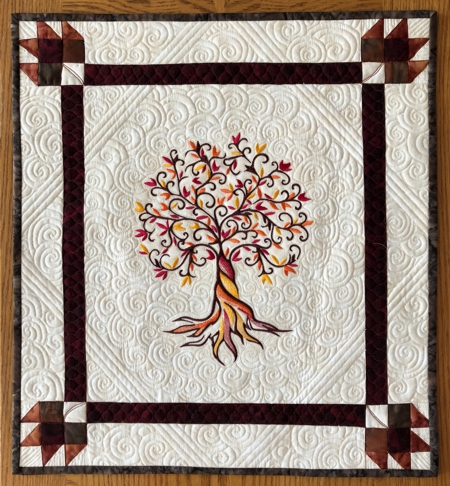 Small wall quilt with autumn tree embroidery.