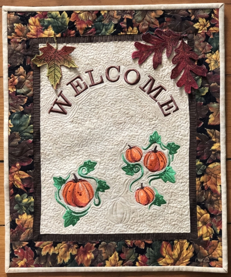 Finished Welcome door quilt with pumpkins and leaves embroidery.