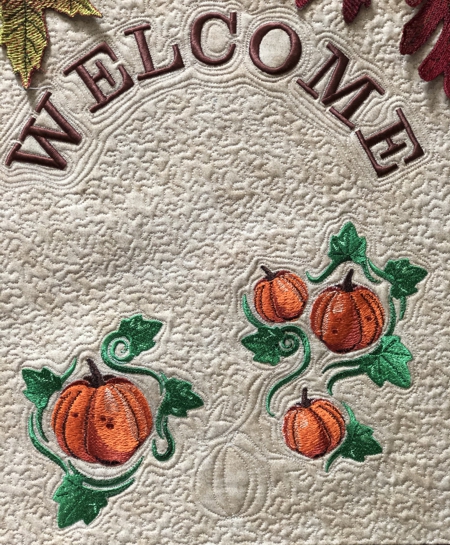 Close-up of the pumpkin and word "welcome" embroidery.