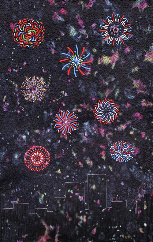 A navy blue wholecloth quilt with fireworks embroidery.