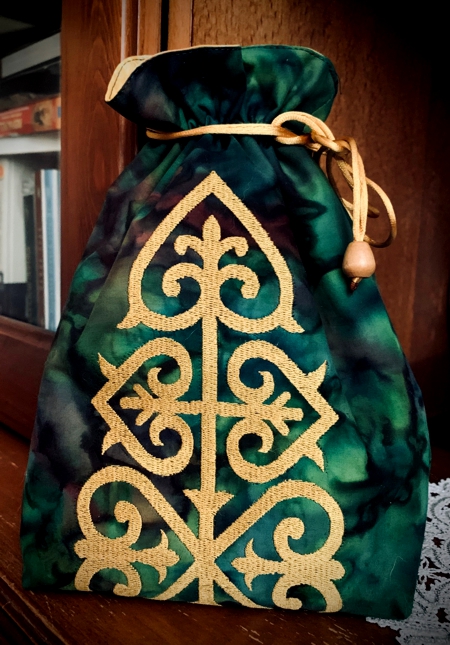 Green gift bag with golden embroidery.