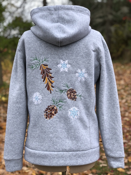 Embroidery of pine cones and snowflakes on the back of a sweatshirt hoody.