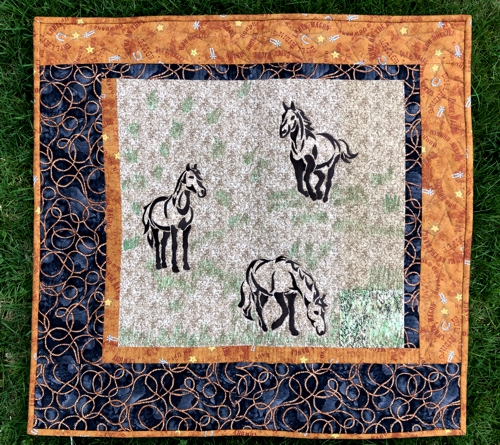 Wall quilt with horse silhouette embroidery.