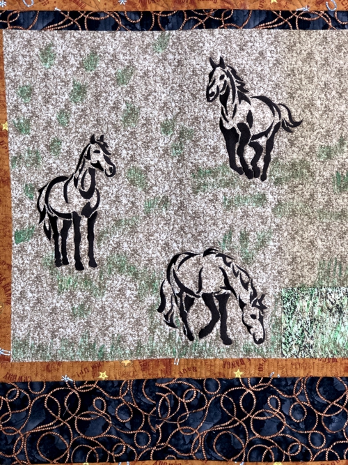 Close-up of the central part of the quilt with horse embroidery.
