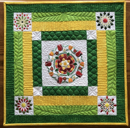 FInished small quilt in yellow and green colors with flower embroidery