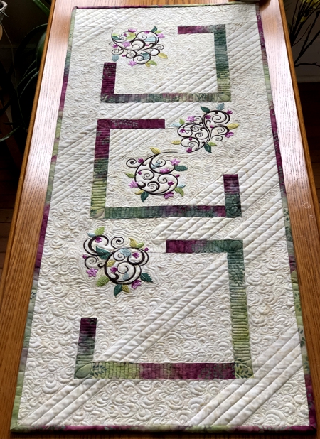 Quilted tablerunner with floral machine embroidery.